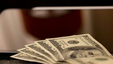 a stack of money sitting on top of a laptop computer