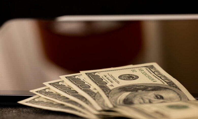 a stack of money sitting on top of a laptop computer
