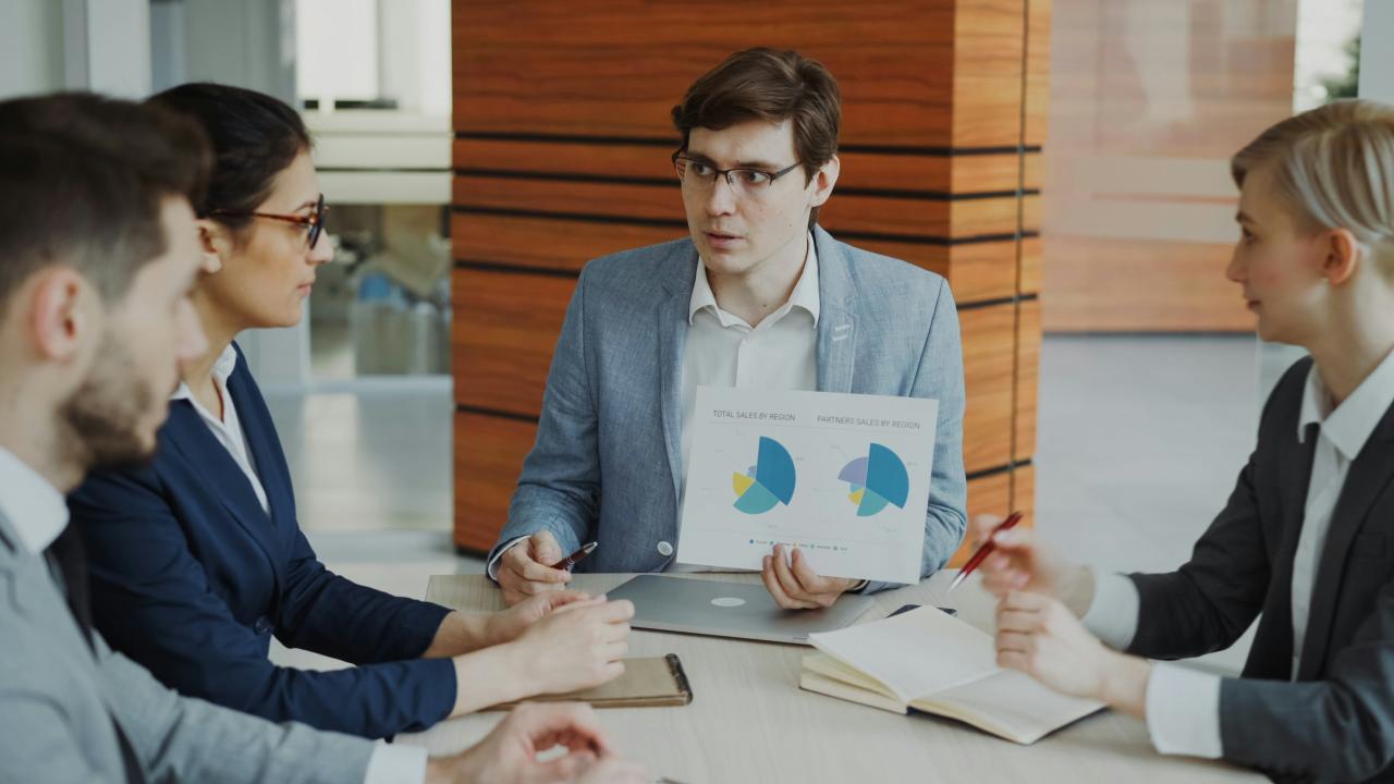 Man presenting charts to colleagues in a meeting.